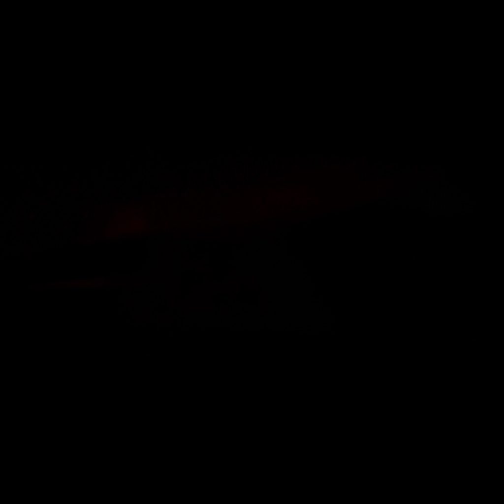 Atmospheric view of a training field at low light, with deep shadows and a quiet amber glow along the fence line.